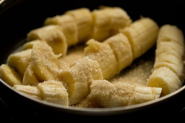 Three rows of sliced bananas topped with sugar in bowl