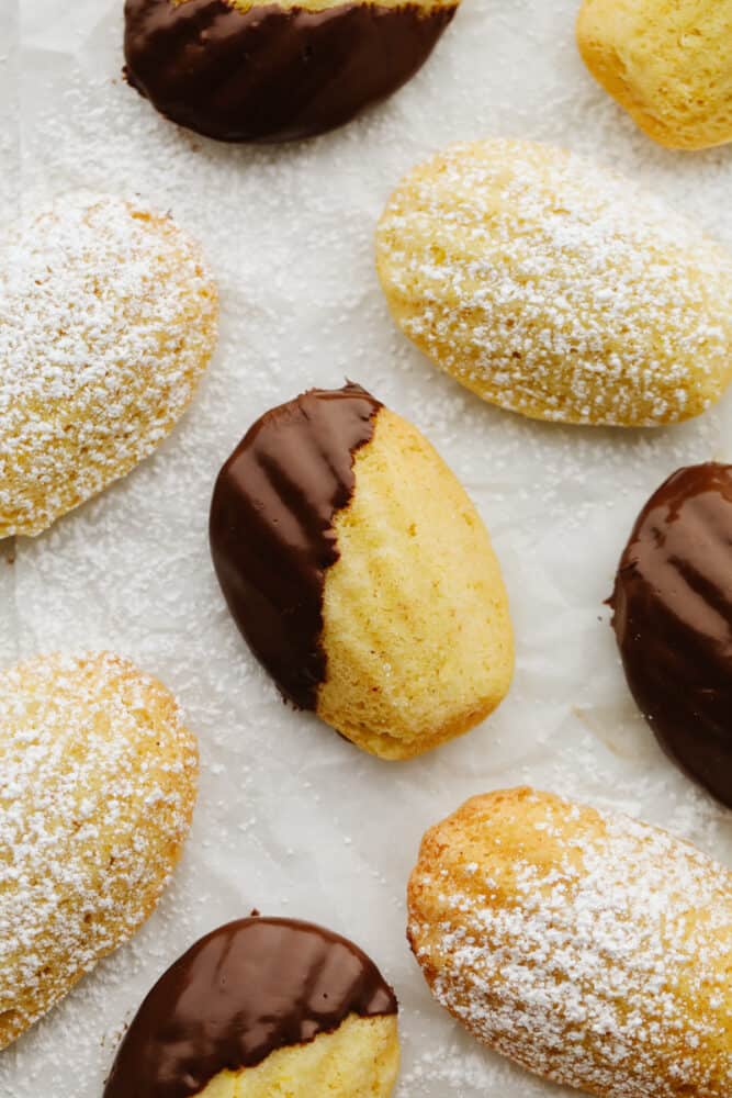 Powdered sugar and chocolate dipped madeleines.