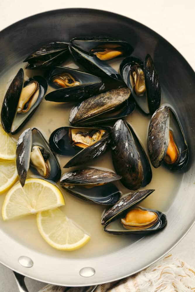 These steamed mussels are easy, elegant, and delicious! They are perfect for any dinner party and you won't be able to stop after just one! Mussels in a pot that are cooked and ready to eat.