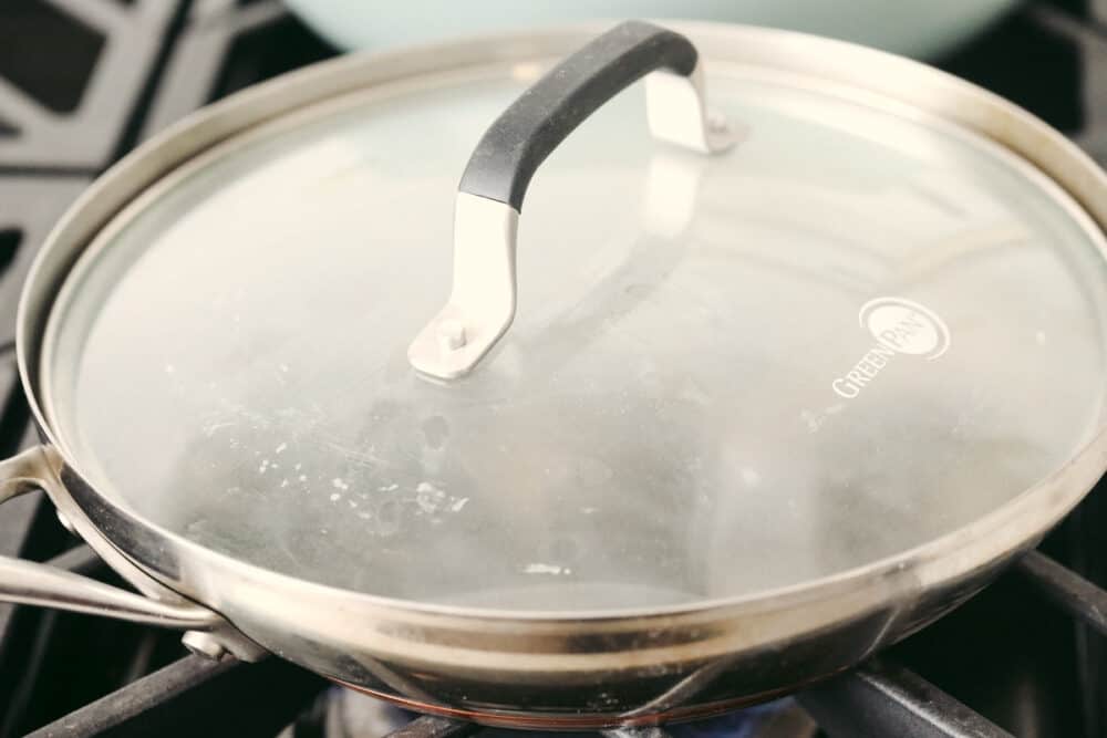These steamed mussels are easy, elegant, and delicious! They are perfect for any dinner party and you won't be able to stop after just one! A pan on the stove with a lid that's full of steam.