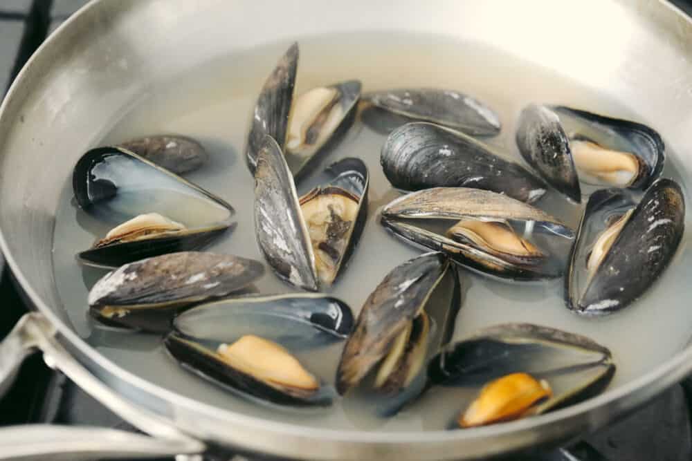 These steamed mussels are easy, elegant, and delicious! They are perfect for any dinner party and you won't be able to stop after just one! Mussels that are fully cooked and open in a pan.