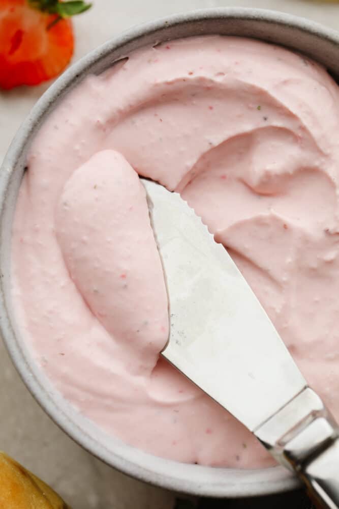 This strawberry cream cheese is rich, creamy, and full of delicious flavor! It's simple to make and will have all of your breakfast bagels tasting SOO GOOD! Cream cheese being served with a butter knife.